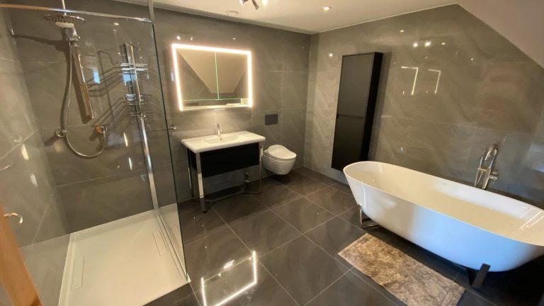 Luxury bathroom featuring a walk-in shower, freestanding bath, LED mirror and contemporary grey wall tiles.
