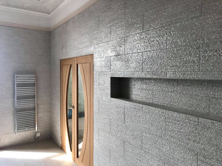 Contemporary bathroom featuring textured wall tiles, a recessed wall niche and a modern wooden door.